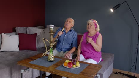 Pareja-De-Ancianos-Fumando-Narguile-En-Casa.-Abuela-Y-Abuelo-Mayores-Divirtiéndose,-Relajándose