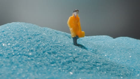 man figure with briefcase walking in desert with blue sand