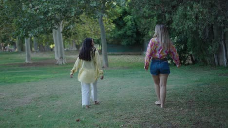 two women friends walking in a park