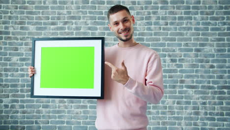 man holding a green screen picture frame
