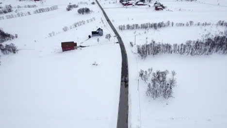 SUV-vehicle-driving-on-a-Norwegian-country-road-in-Norway,-Revealing-shot-of-scenery-landscape