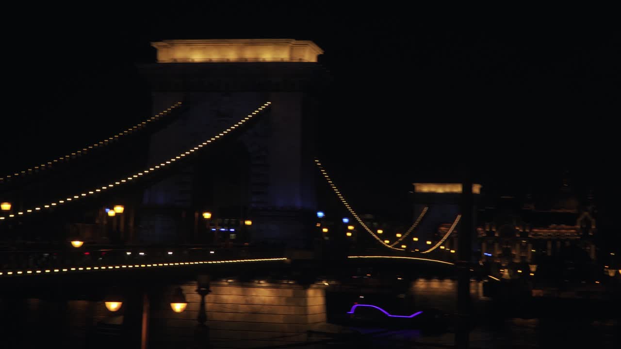 The Famous Szechenyi Chain Bridge Spanning Over The Danube River In Budapest Hungary At Night-Time - Panoramic Shot