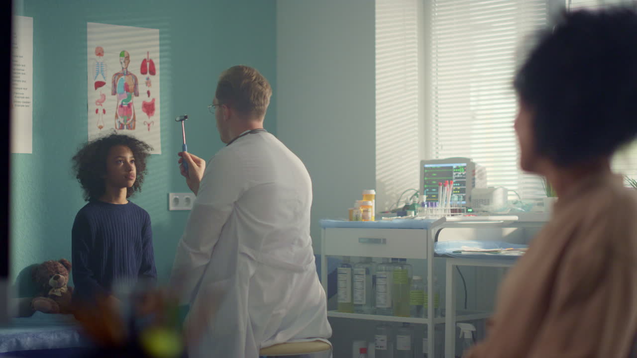 Pediatrician checking preteen girl visual reflex using neurological hammer.