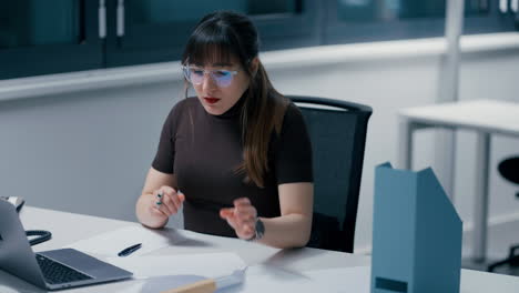 Nahaufnahme-Einer-Jungen,-Schönen,-Dunkelhaarigen-Frau,-Die-Im-Büro-Mit-Einem-Laptop-An-Ihren-Papieren-Arbeitet,-Ihre-Brille-Abnimmt-Und-Bei-Der-Arbeit-In-Zeitlupe-Erschöpft,-Müde-Und-Gestresst-Ist