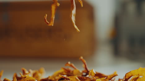 Detail shot of a man&#039;s hand picking up yellow aromatic dried spice herbs from a table