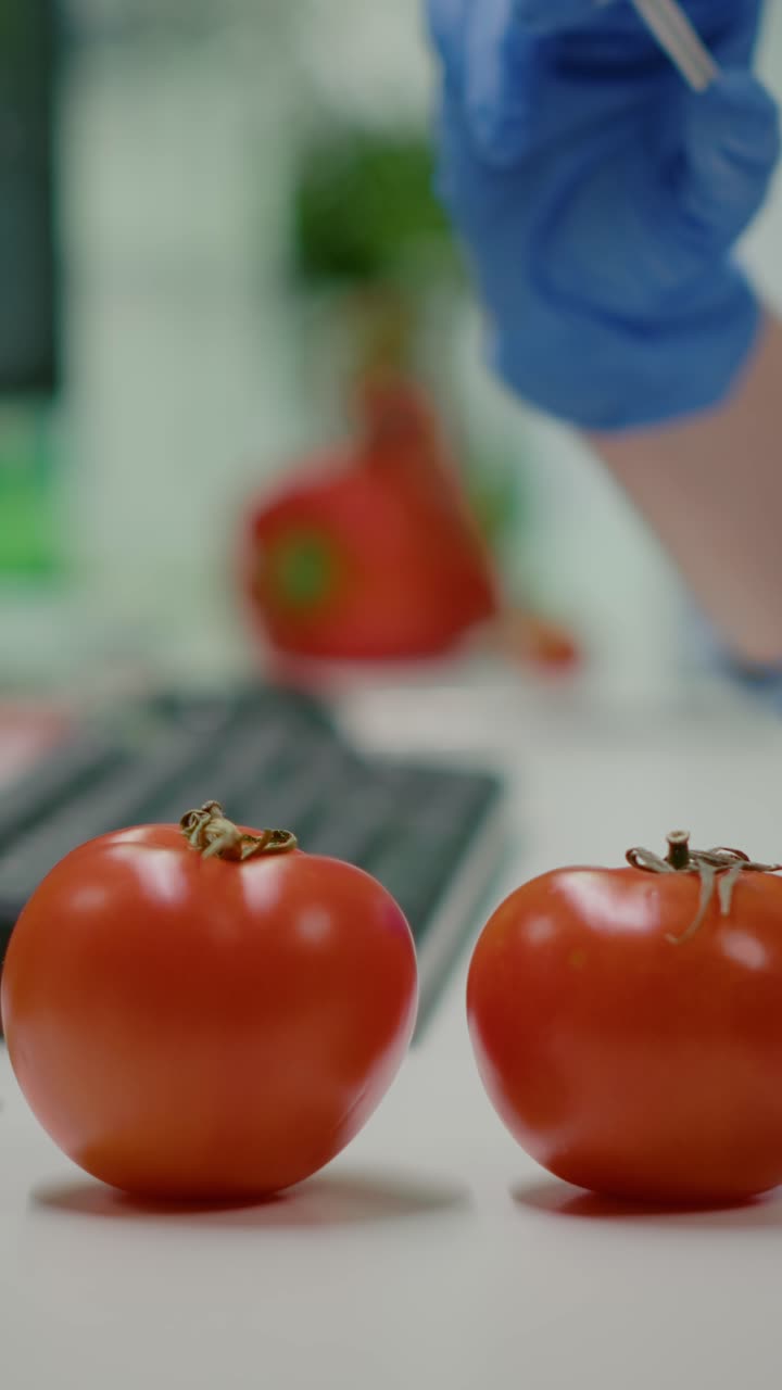 Close-up of a scientist's gloved hand injecting a syringe into a tomato, representing genetic modification or food research