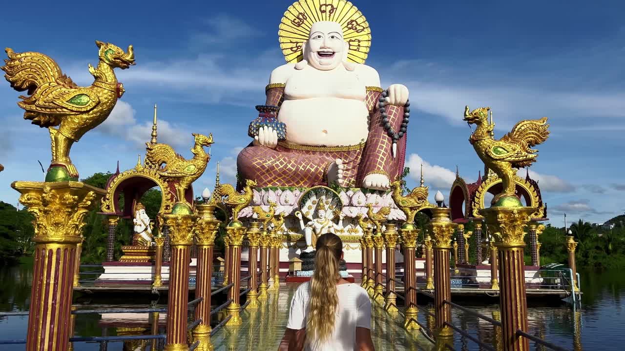 긴 금발 머리를 가진 소녀가 불상을 향해 걷고 있다