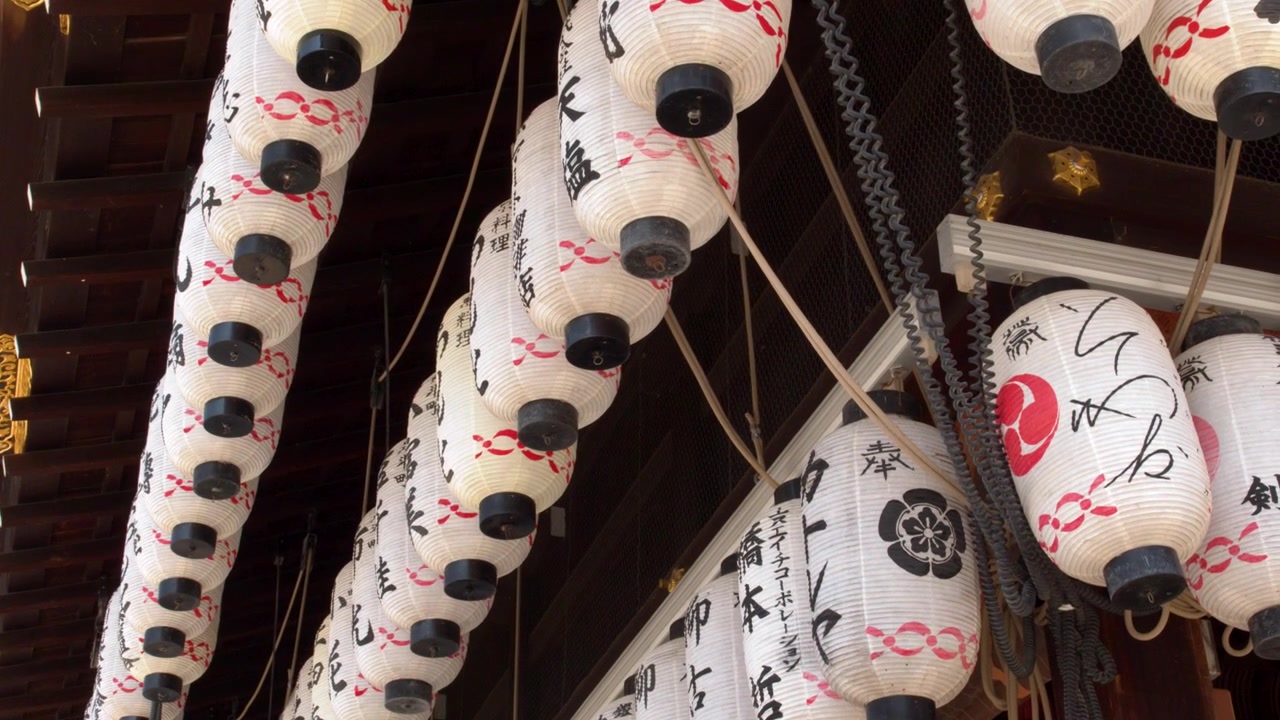 京都の寺院の軒下につるされた、書道が施された白い提灯のローアングル。