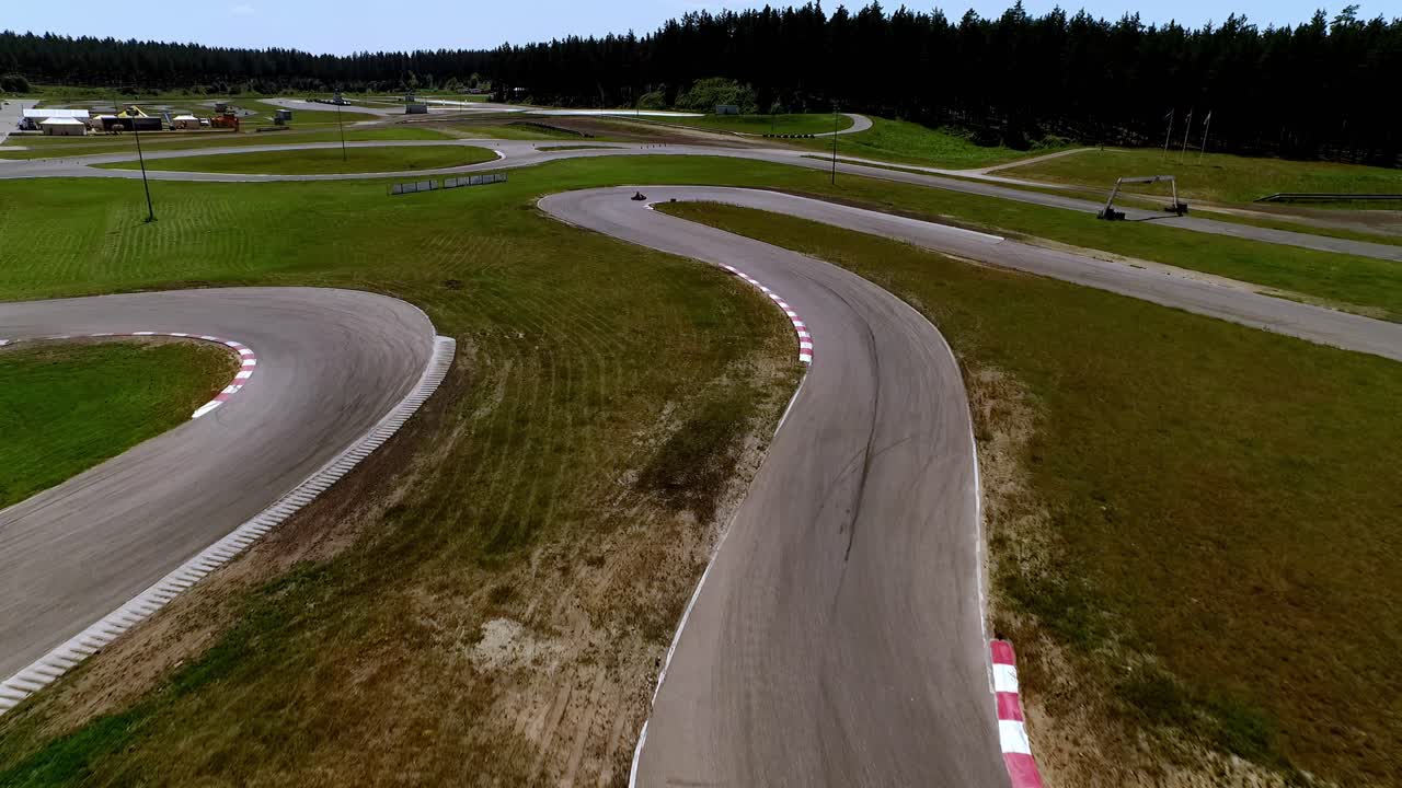 Latvia's Racing Heart Aerial View of a Winding Go-Kart Track, with Karts Zipping Around Bends and Lush Green Forests Framing the Scene - Wide-Angle Lens Shot