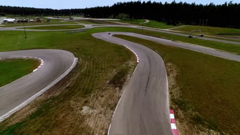 latvia's racing heart aerial view of a winding go-kart track, with karts zipping around bends and lush green forests framing the scene - wide-angle lens shot