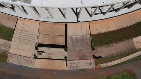 Aerial-drone-footage-of-a-truck-moving-across-a-parking-lot-outside-a-soccer-stadium