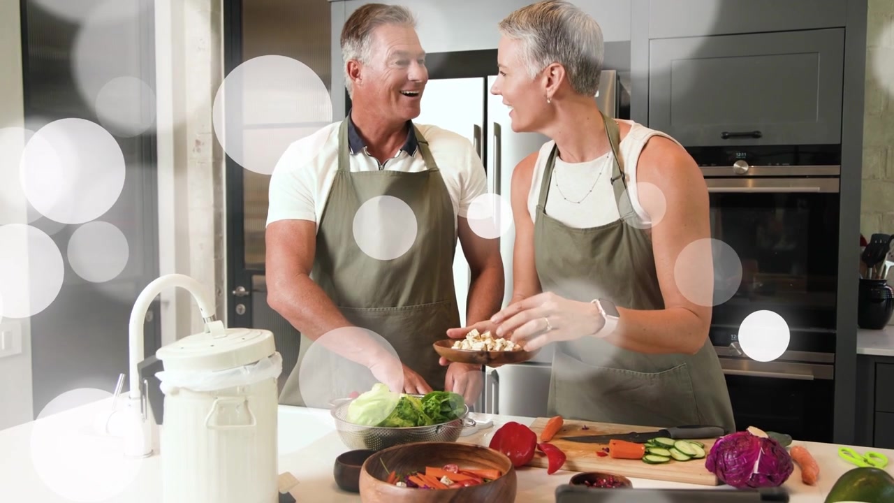 Mann spült Salat und Frau prüft Tablet, um die Salatzubereitung in der Küche anzuleiten, mit Bokeh-Effekt.