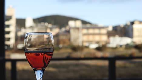 wine glass slowly empties against a cityscape.