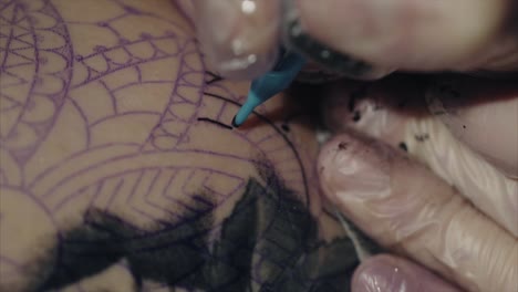artista del tatuaje que dibuja un diseño complejo en un brazo
