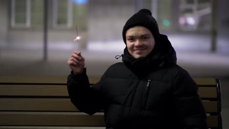 teenager with sparkler on a park bench at night