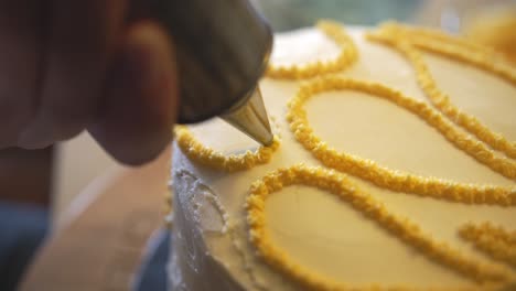 Close-up-of-cake-being-frosted-with-yellow-frosting,-very-sharp-focus