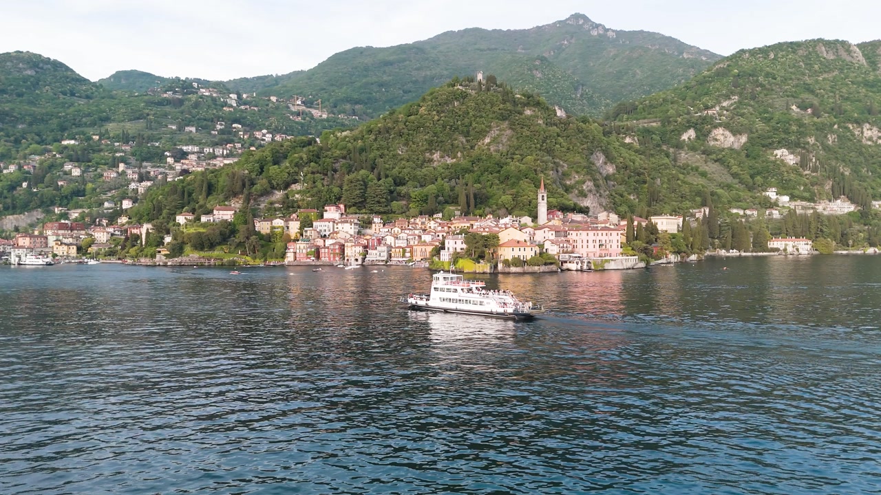 Drone view of Varenna before sunset, capturing a ferry gliding back across Lake Como.