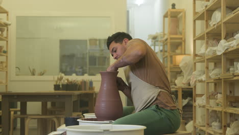 Male-artisan-craftsman-shaping-handmade-vase-sculpture-on-workshop-pottery-wheel