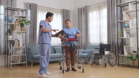 아시안 남성 간호사가 태블릿에 의학적 검사 결과를 보여주고 집에서 물리 치료를 하는 동안 워커에서 환자에게 설명합니다.