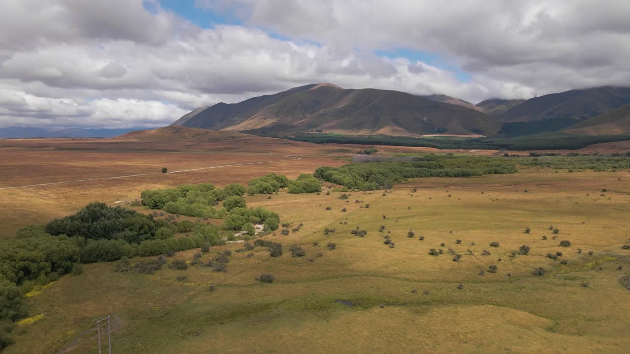 강을 따라 산맥을 향해 무성한 나무가 늘어선 광활하고 야생의 풍경을 가로지르는 곡선 드론 비행