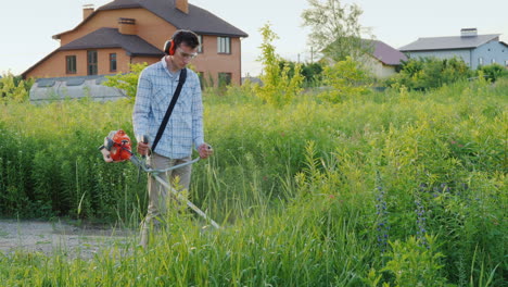 Man-Mows-Weeds-Around-The-House-With-A-Trimmer