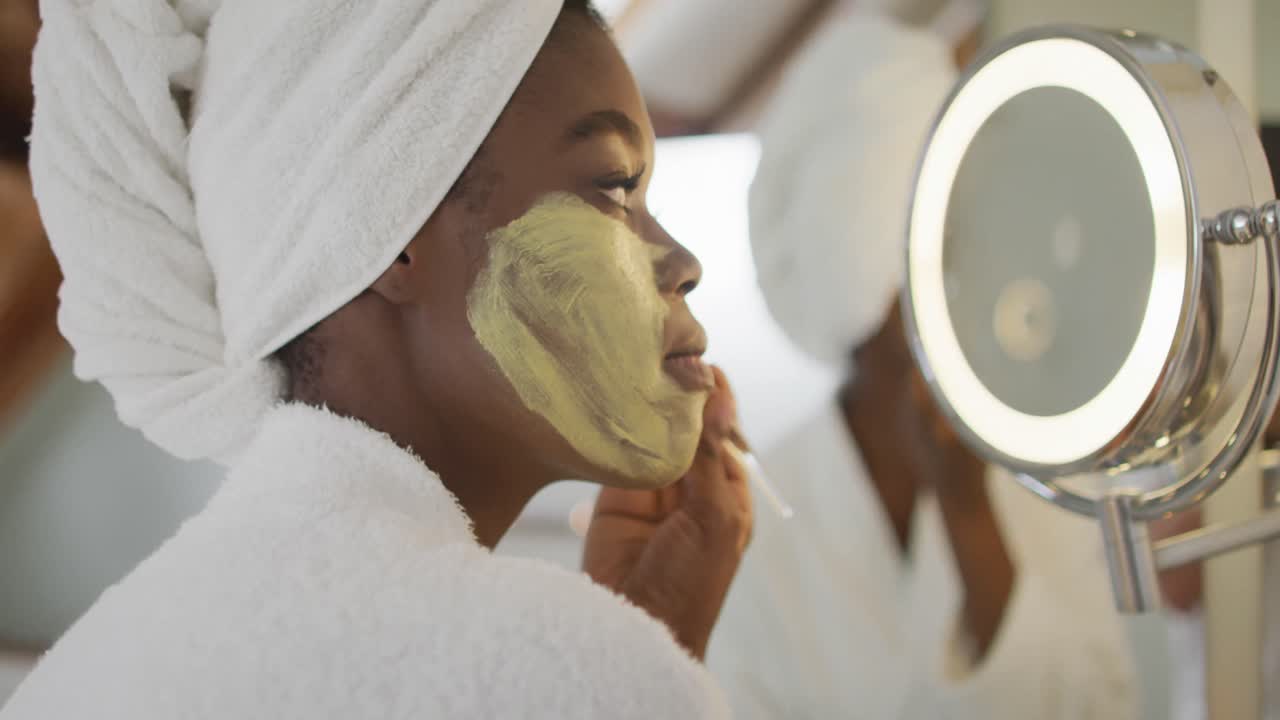 Perfil de mulher negra atraente aplicando máscara facial no banheiro