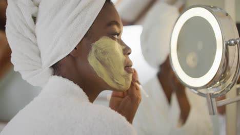 Profile-of-african-american-attractive-woman-applying-face-mask-in-bathroom