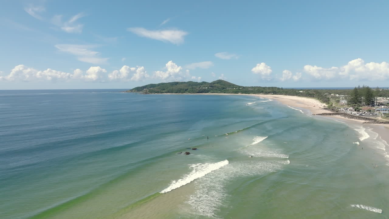 Done shot over Byron Bay coastline showing surfers in the ocean, on a sunny day. Australia
