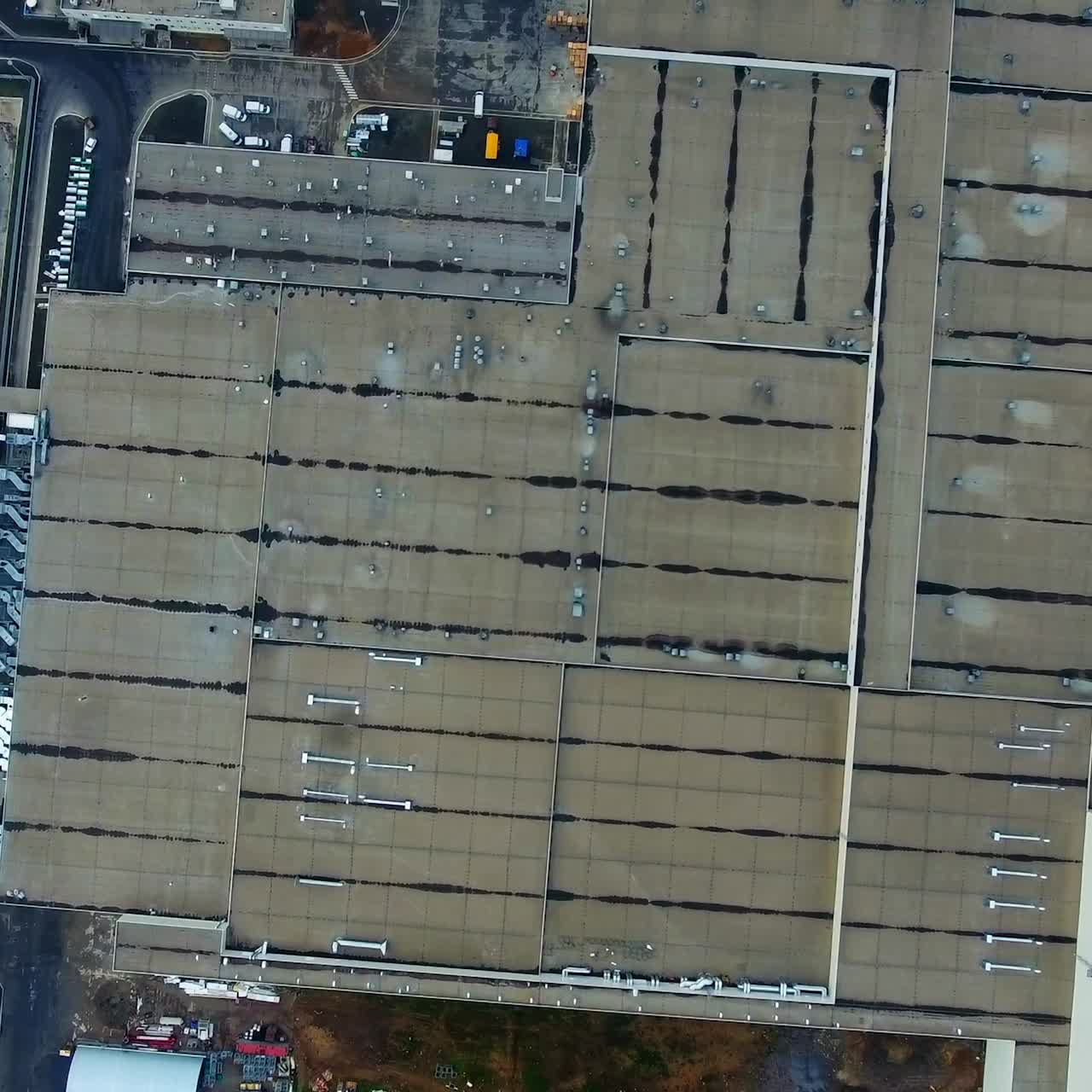 Factory on green field. View from above on industrial territory and many cars nearby. Gray roofs from above