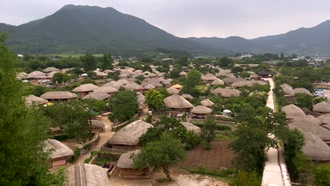 aerial panorama shot of traditional village in south korea in rural landscape with mountains during clouds at sky - naban eupseong folk village