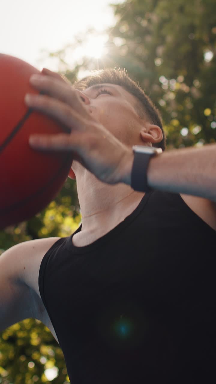 Hombre atlético con ropa deportiva jugando al baloncesto lanza con éxito la pelota al anillo de la canasta