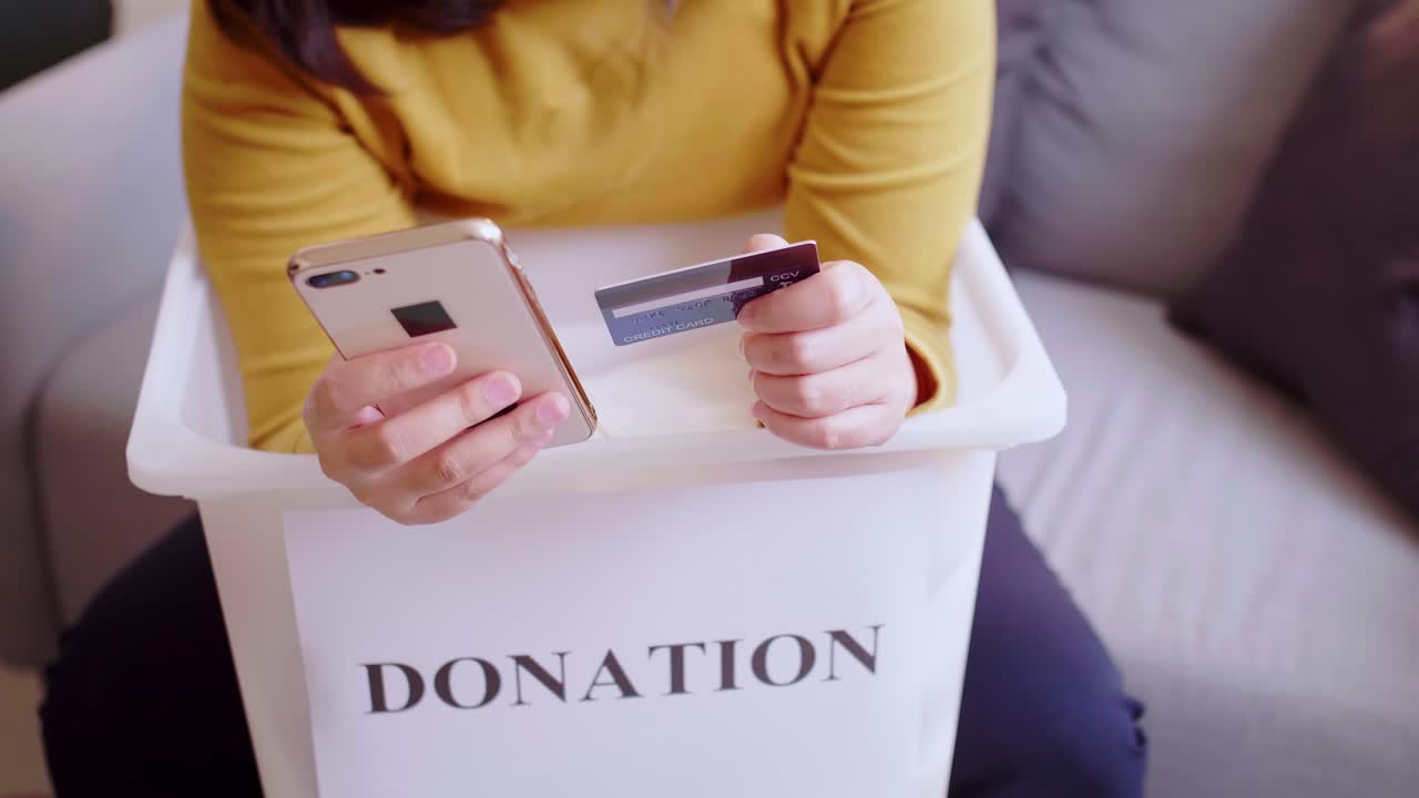 Detail of female hands making a donation with a credit card