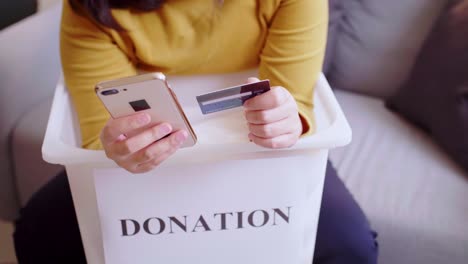 Detalle-De-Manos-Femeninas-Haciendo-Una-Donación-Con-Tarjeta-De-Crédito