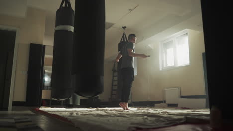 uomo sportivo si esercita con la corda da salto in palestra. kickboxer muscolare salta sulla corda da saltare nel club di arti marziali slow motion. sviluppo della resistenza del corpo