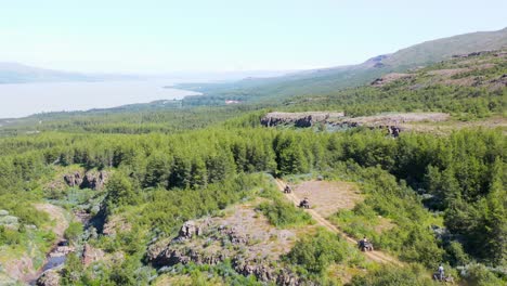 Tourist-on-quadbikes-driving-through-beautiful-natural-forest-landscape,-aerial