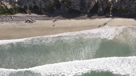 A-stunning-birds-eye-static-aerial-drone-shot-of-people-walking-on-the-beach,-Carlsbad-State-Beach---California