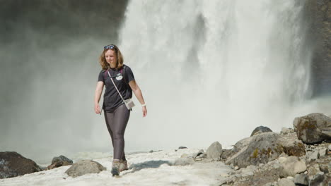 Woman-walking-on-icy-path,-Moul-Falls-in-background,-Canada