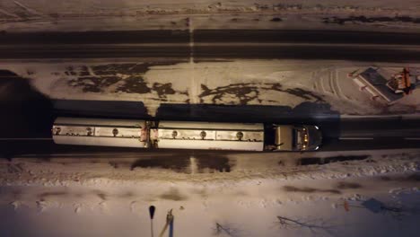 Toma-De-Seguimiento-Aéreo-Después-De-Un-Camión-Que-Circula-Por-Una-Carretera-Con-Nieve-A-Los-Lados