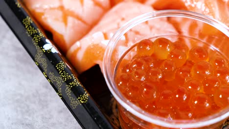 close up rotate movement of ikura (salmon roe) and salmon sashimi on dish, japanese food