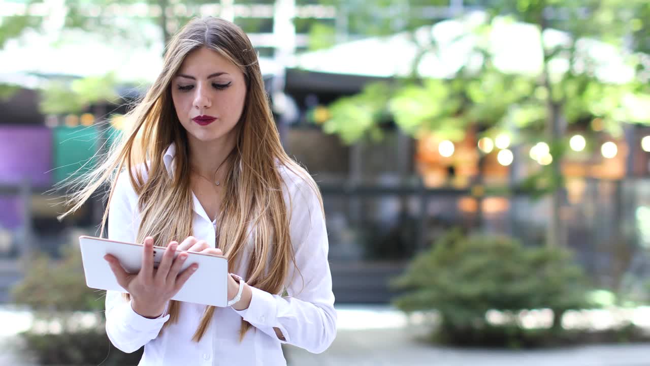 mujer de negocios sonriente usando una tableta digital al aire libre