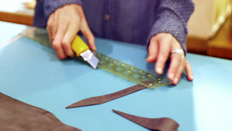 mid-section of craftswoman cutting leather