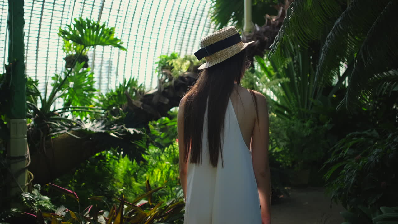 울창 한 온실 정원 을 탐험 하는 여자