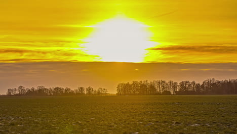 breathtaking sunset on a farmland field with forests on the horizon