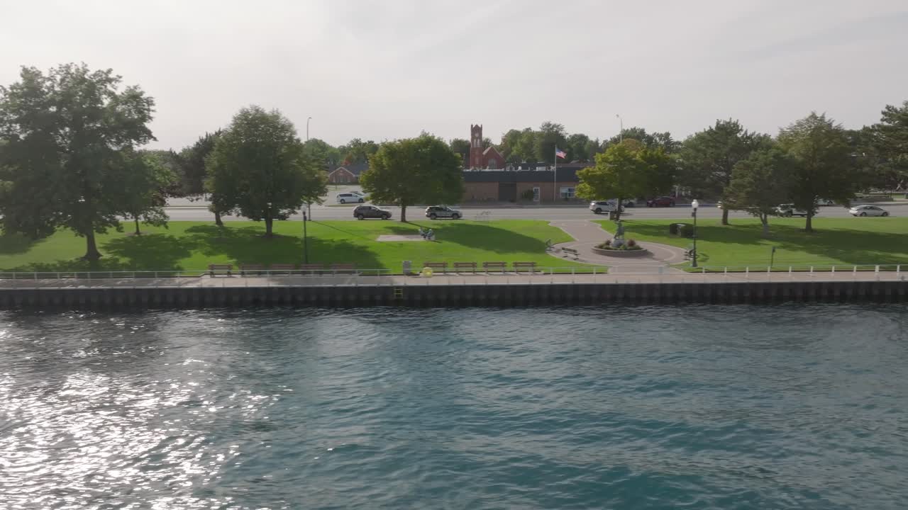 Drönarbild tagen från vänster till höger nära vattenytan från Saint Clair River längs strandpromenaden i Saint Clair, Michigan
