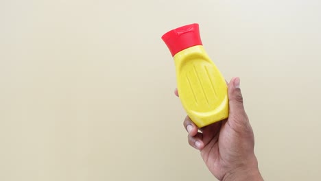 hand holding yellow mustard bottle