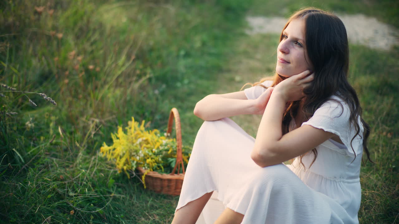 Pensive girl sitting in tall grass dreaming