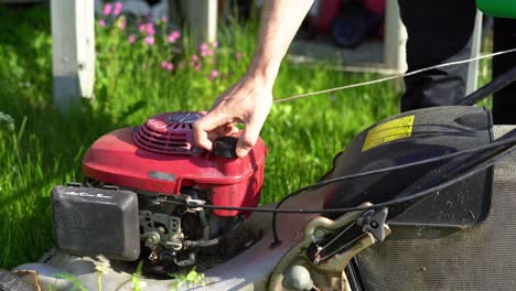 Tripod-shot-of-refueling-a-lawn-mower-with-gasoline-on-a-sunny-day-in-a-garden,-spilling-petrol