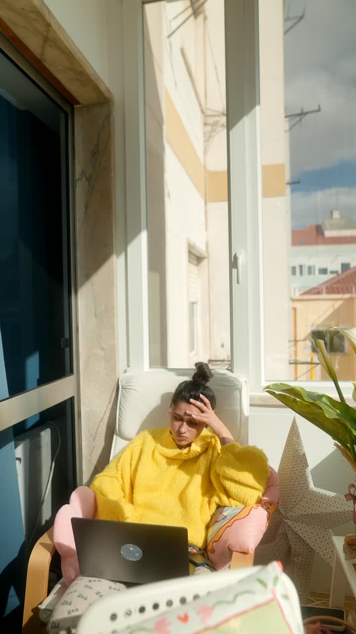 Giovane donna concentrata al laptop mentre lavora da casa