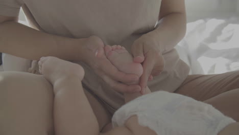 mamá masajeando y acariciando los pies de su bebé