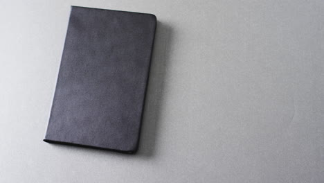 close up de un libro negro cerrado con espacio de copia en un fondo gris en cámara lenta